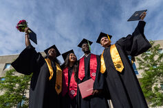 Four IUPUI graduates holding their diplomas